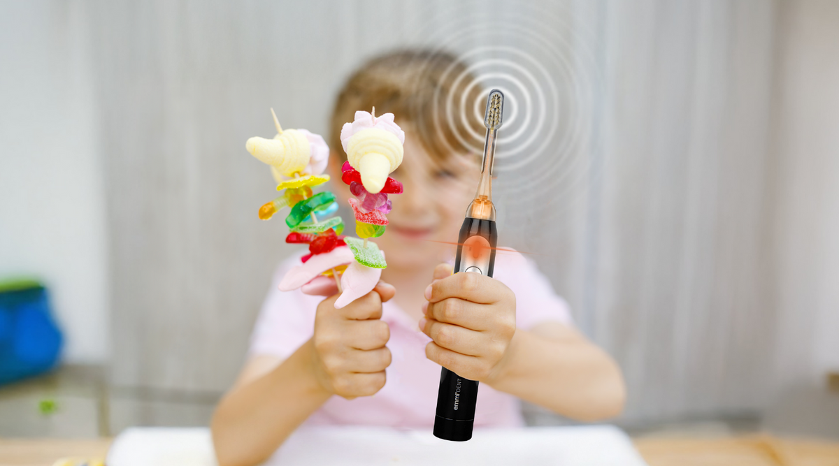Kind mit Zahnbürste und Süßigkeiten in der Hand