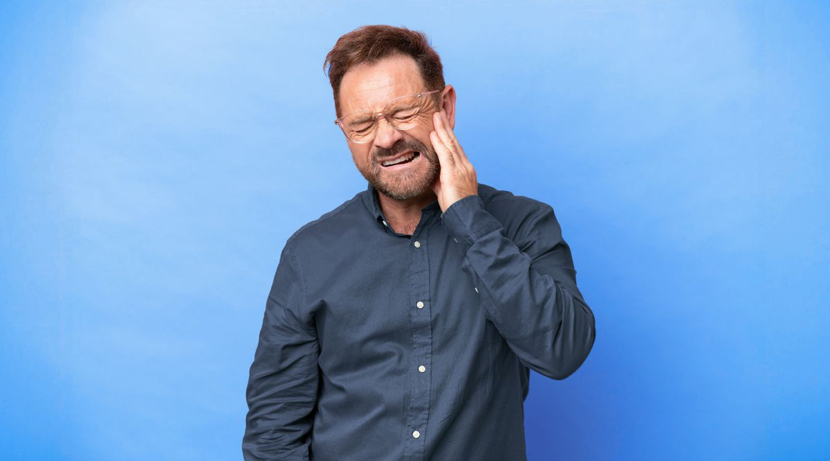 Mann reibt sich morgens den Kiefer im Badezimmer
